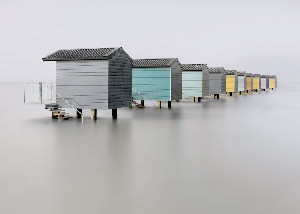 Osea beach huts standing above the water at high tide on the Blackwater Estuary in Essex.